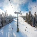 Beautiful mountain winter scene with chairlift and skiers at the ski resort. Winter vacation concept