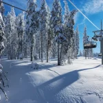 Solrig morgen i Rhodope-bjergene, skisportsstedet Pamporovo. Stolelift over fyrretræer. Snejanka TV-tårn i baggrunden. Koncept for sport og rekreation. Selektivt fokus.