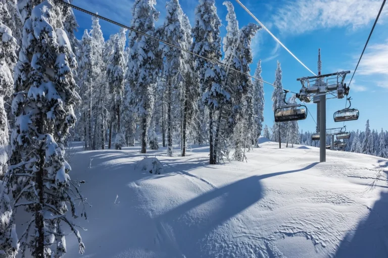 Sunny morning in the Rhodope Mountains, ski resort Pamporovo. Chair ski lift over pine trees. Snejanka TV tower in  background. Sports and recreation concept. Selective focus.